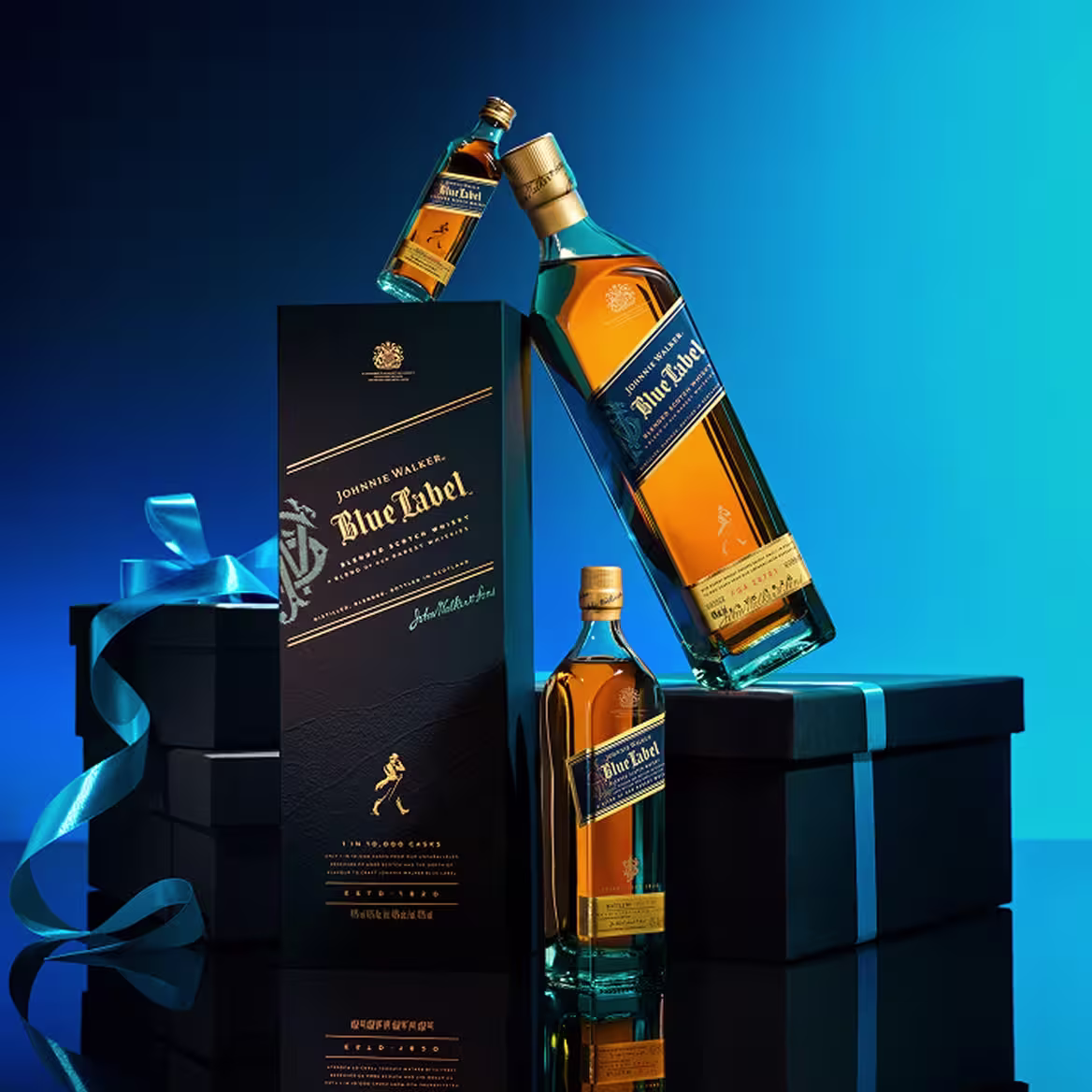 A bottle of Johnnie Walker Blue Label whisky stands beside its elegant black box and two gift boxes with blue ribbons, with another smaller bottle and a tilted bottle displayed on a blue gradient background.