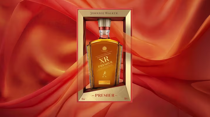 裝在金色禮盒中的尊尼獲加（Johnnie Walker）XR Premier 威士忌酒瓶，背景為流動的橙色絲綢。