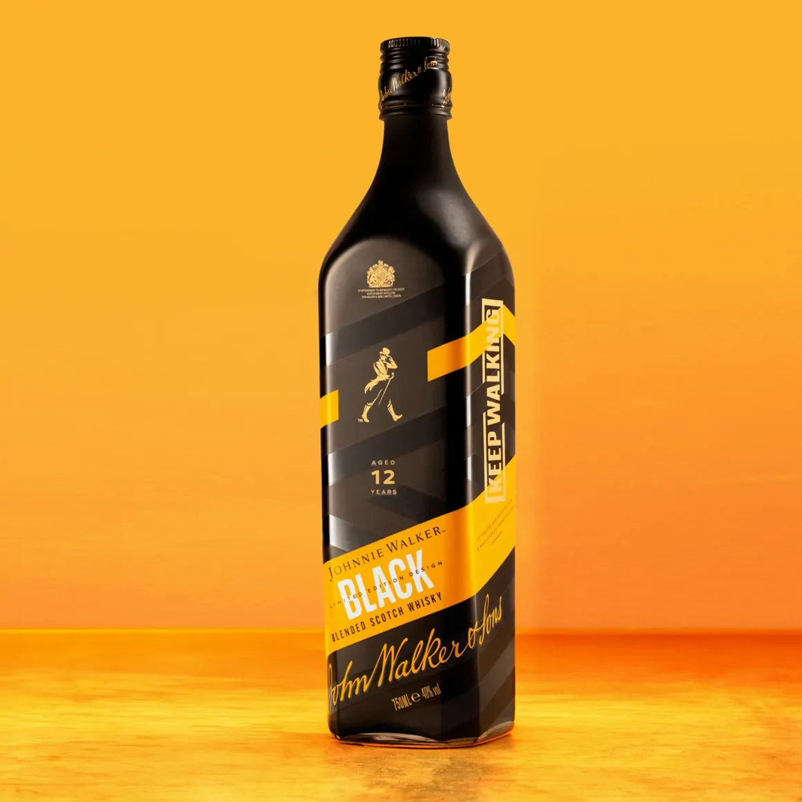 Uma garrafa de uísque escocês Johnnie Walker Black Label blended em um fundo laranja brilhante. A garrafa apresenta um rótulo preto e amarelo com o slogan Keep Walking e é marcada como 12 anos envelhecido.