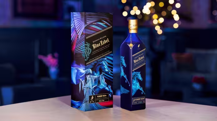 一瓶藍色的尊尼獲加藍牌馬年威士忌，配有一個飾有藍色駿馬圖案的同款裝飾盒，擺放在背景模糊的桌子上。