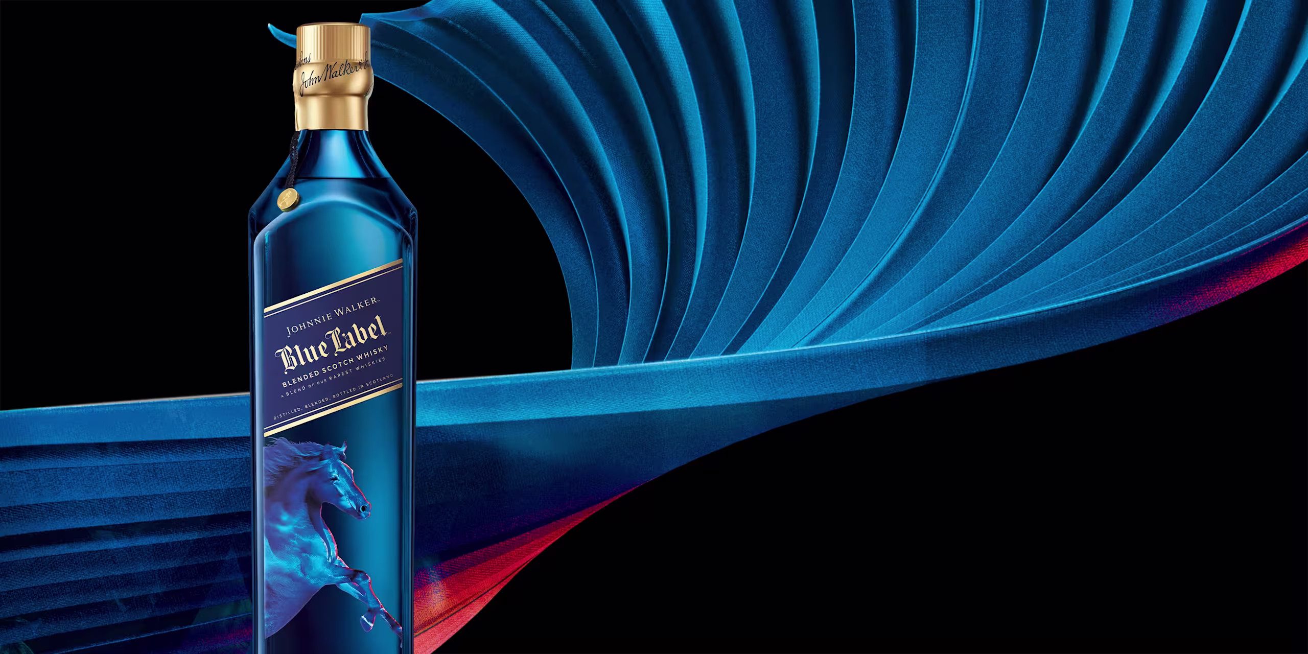Butelka whisky Johnnie Walker Blue Label z ilustracją niebieskiego konia z przodu, na tle wirującego, abstrakcyjnego tła w odcieniach błękitu i czerwieni.