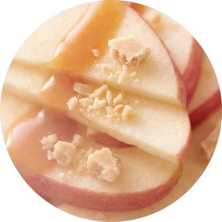 Appelschijfjes bedekt met karamelsaus en bestrooid met gehakte noten, van dichtbij weergegeven.