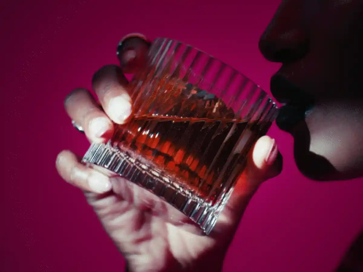 A person drinking whisky from a glass