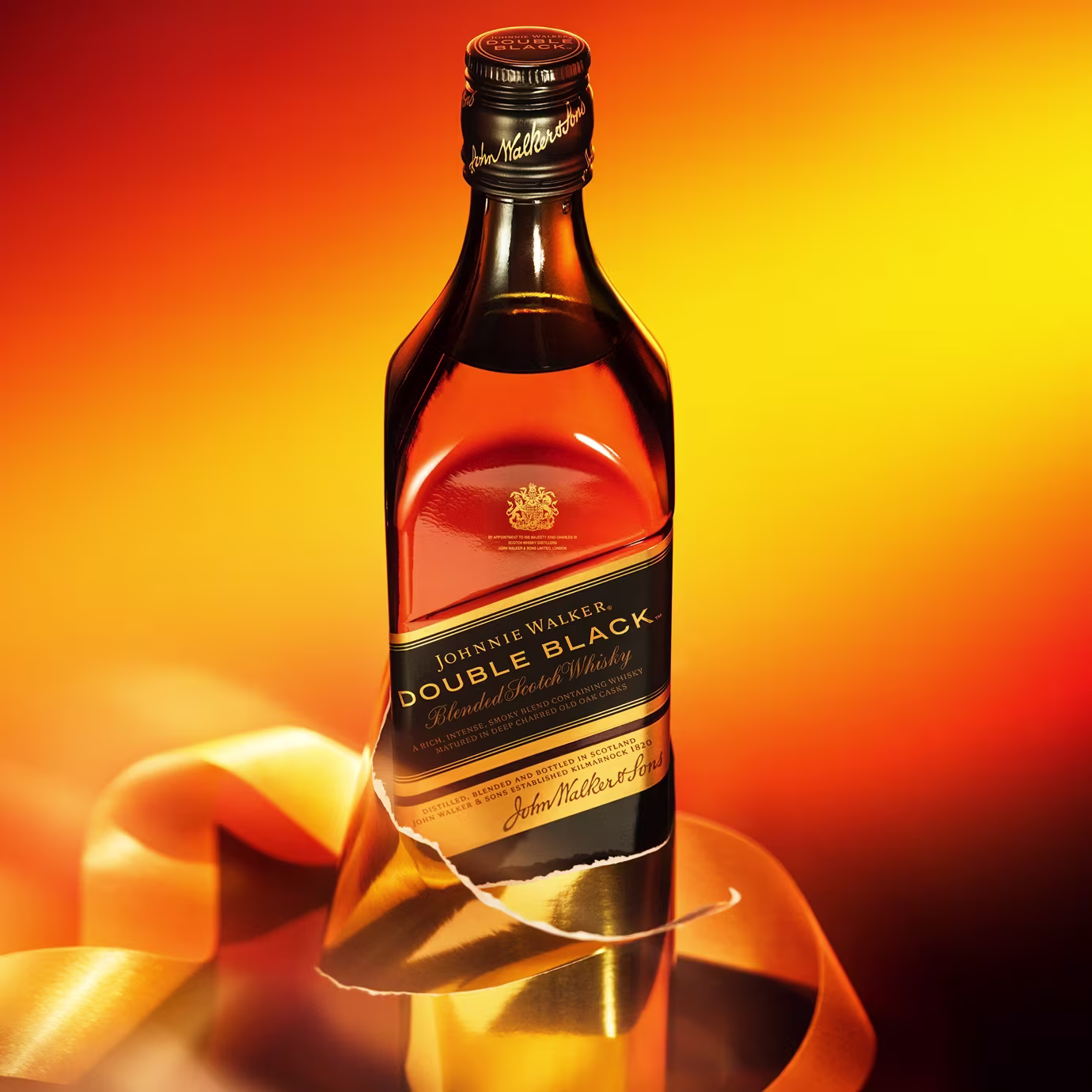 A bottle of Johnnie Walker Double Black whisky with gold ribbon on an orange gradient background.