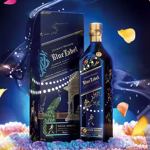 A limited edition Johnnie Walker Blue Label bottle and box featuring intricate, colorful designs with peacocks, flowers, and a pavilion, set against a dark blue background with floating petals and soft, colorful lighting.