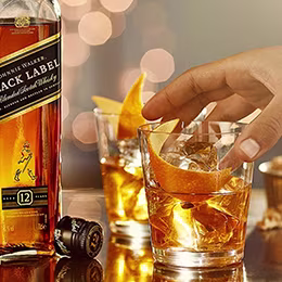 Two glasses with whiskey, orange peel garnish.