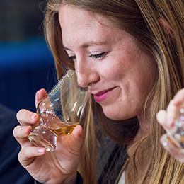 Person enjoying whiskey aroma, smiling.