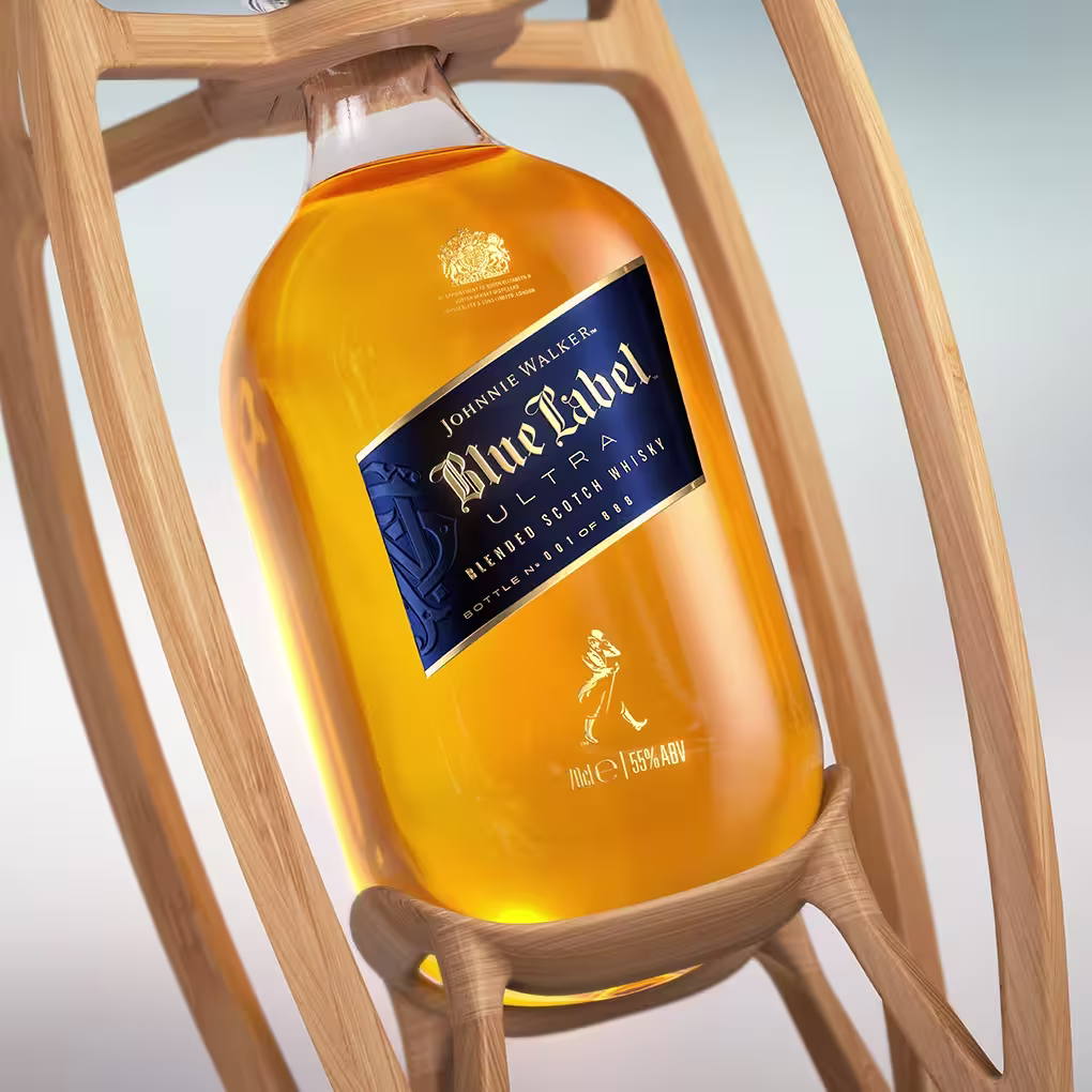 A close-up of a Johnnie Walker Blue Label bottle filled with amber whisky, cradled in a stylish wooden holder, against a soft blue and white background.