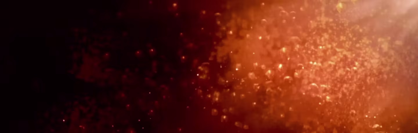Blurred image with orange and red tones with spots of light resembling bokeh or abstract light reflections scattered throughout the background.