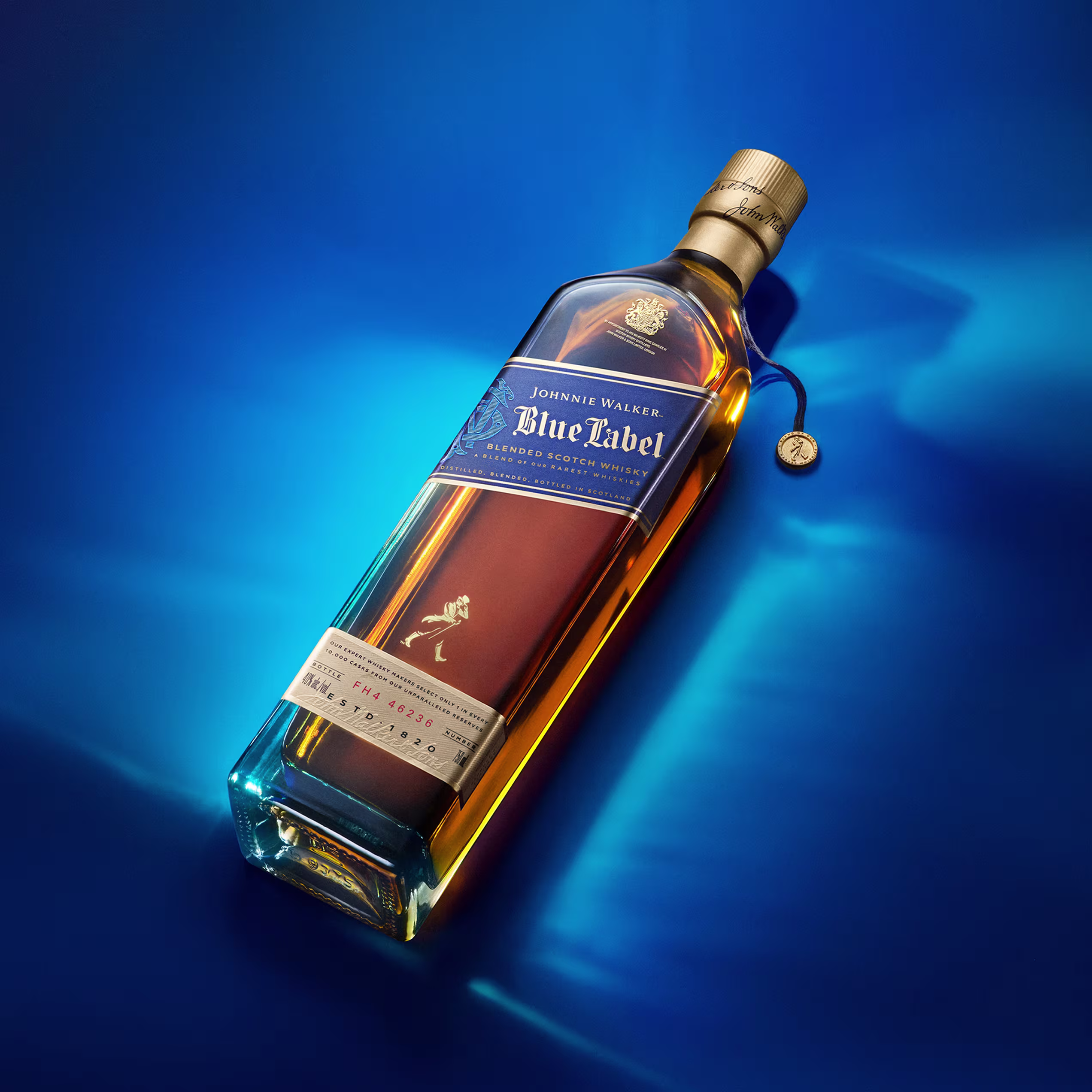 A bottle of Johnnie Walker Blue Label lying on a vivid blue surface with soft light reflections.