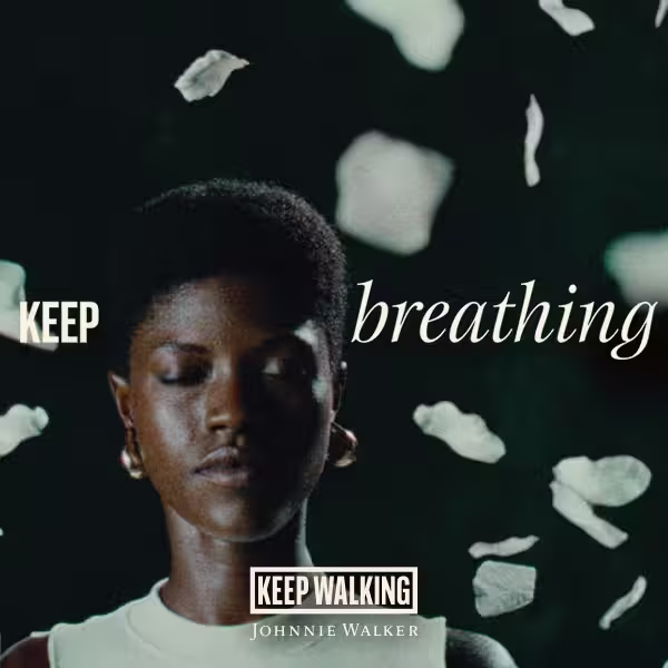 A person with closed eyes stands against a dark background with white petals falling. The words KEEP breathing appear, along with the Johnnie Walker logo and the phrase KEEP WALKING at the bottom.
