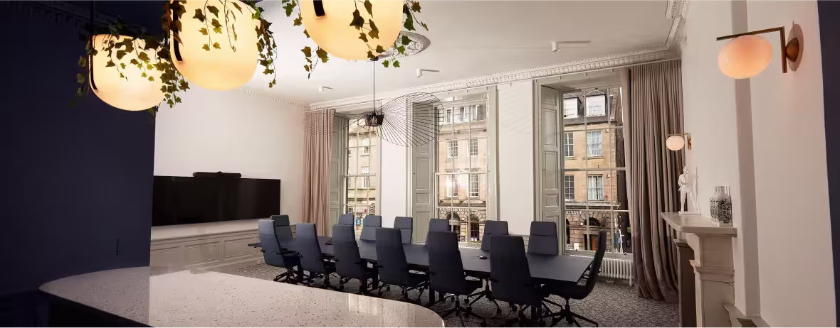 A conference room with a large table and chairs, with a view of a city street through the windows.