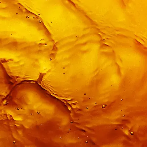  Abstract close-up of a bright yellow and orange liquid with gently flowing patterns and scattered bubbles creating an organic, dynamic texture.