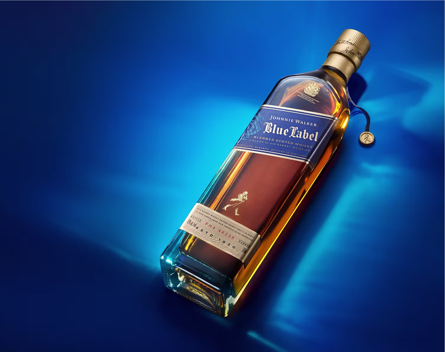 A Johnnie Walker Blue Label whisky bottle lies on a vibrant blue surface with a golden cap.