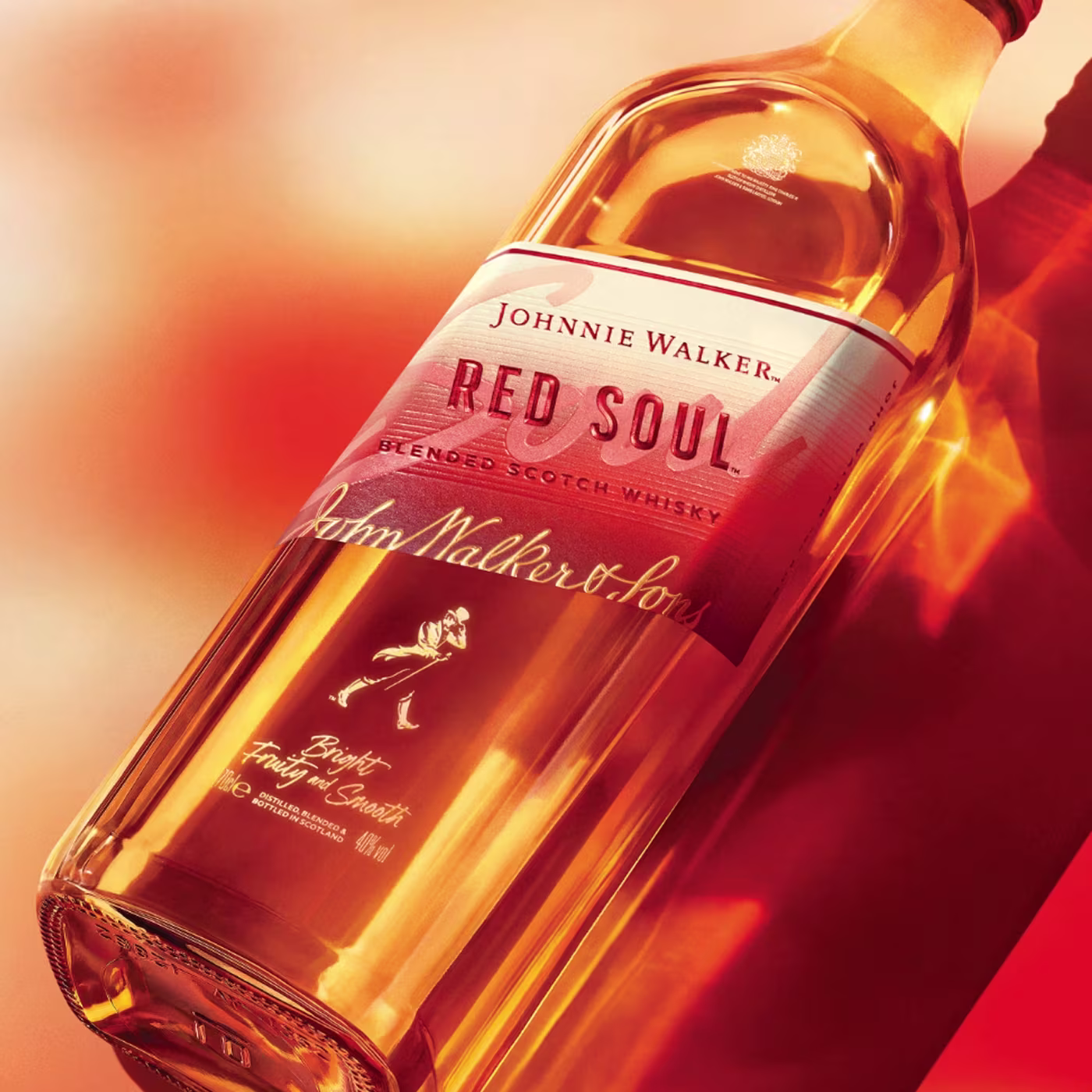 Butelka szkockiej whisky Johnnie Walker Red Soul Blended na czerwonym i pomarańczowym tle.
