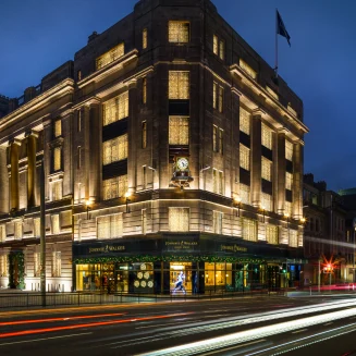 Una toma exterior de un gran edificio con luces en las ventanas de noche.