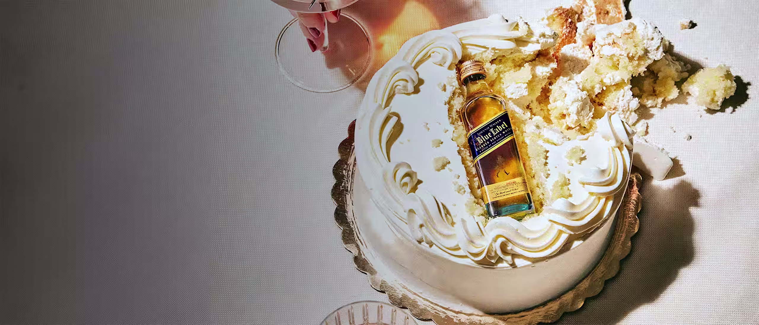 Small cake with whisky bottle inside, red cocktail, amber drink.