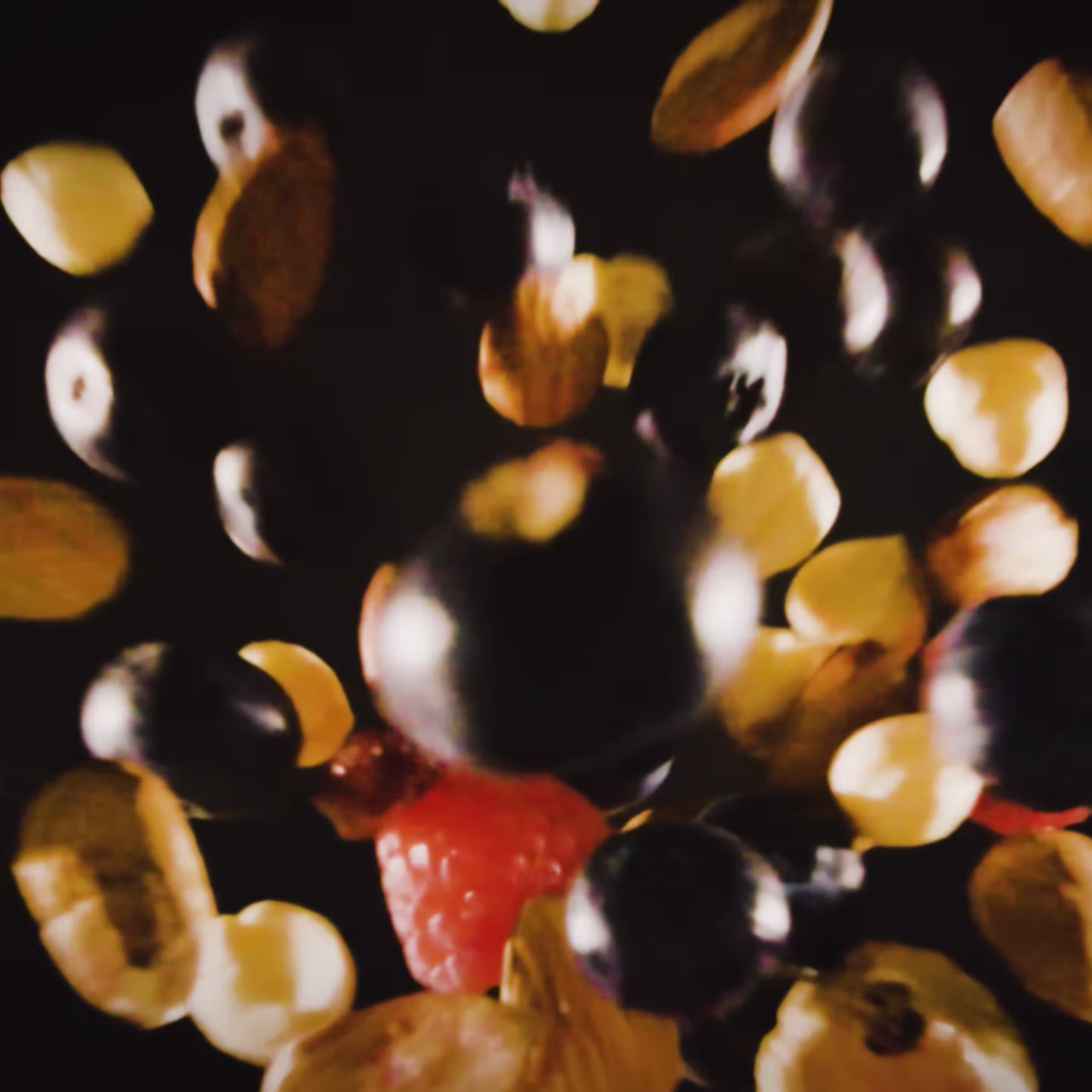 A mix of berries and sliced grapes in mid-air against a dark background, giving a sense of motion and freshness.