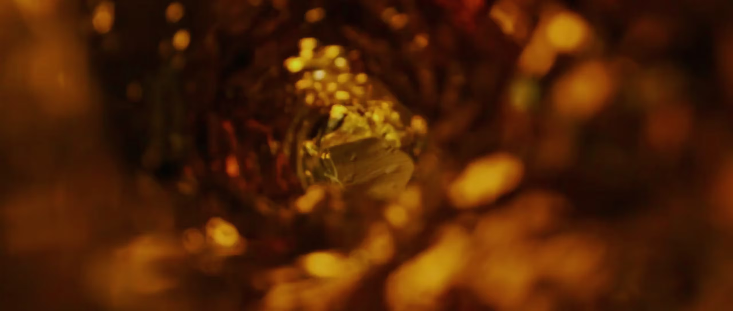 View from inside a tunnel or tube with warm golden light surrounding it, creating a blurred, abstract effect with bokeh highlights and a soft focus towards the center.