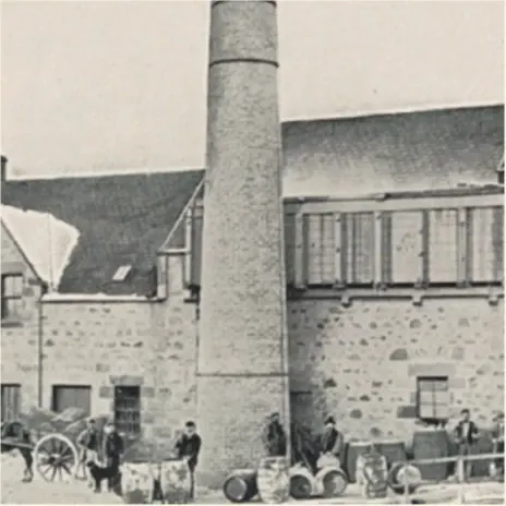  Vintage-Schwarz-Weiß-Foto einer Brennerei mit einem hohen Schornstein davor. Mehrere Menschen stehen neben gestapelten Fässern und Karren. Das Gebäude hat Steinmauern und kleine Fenster. Die Szene zeigt industrielle Aktivitäten aus einer früheren Zeit.