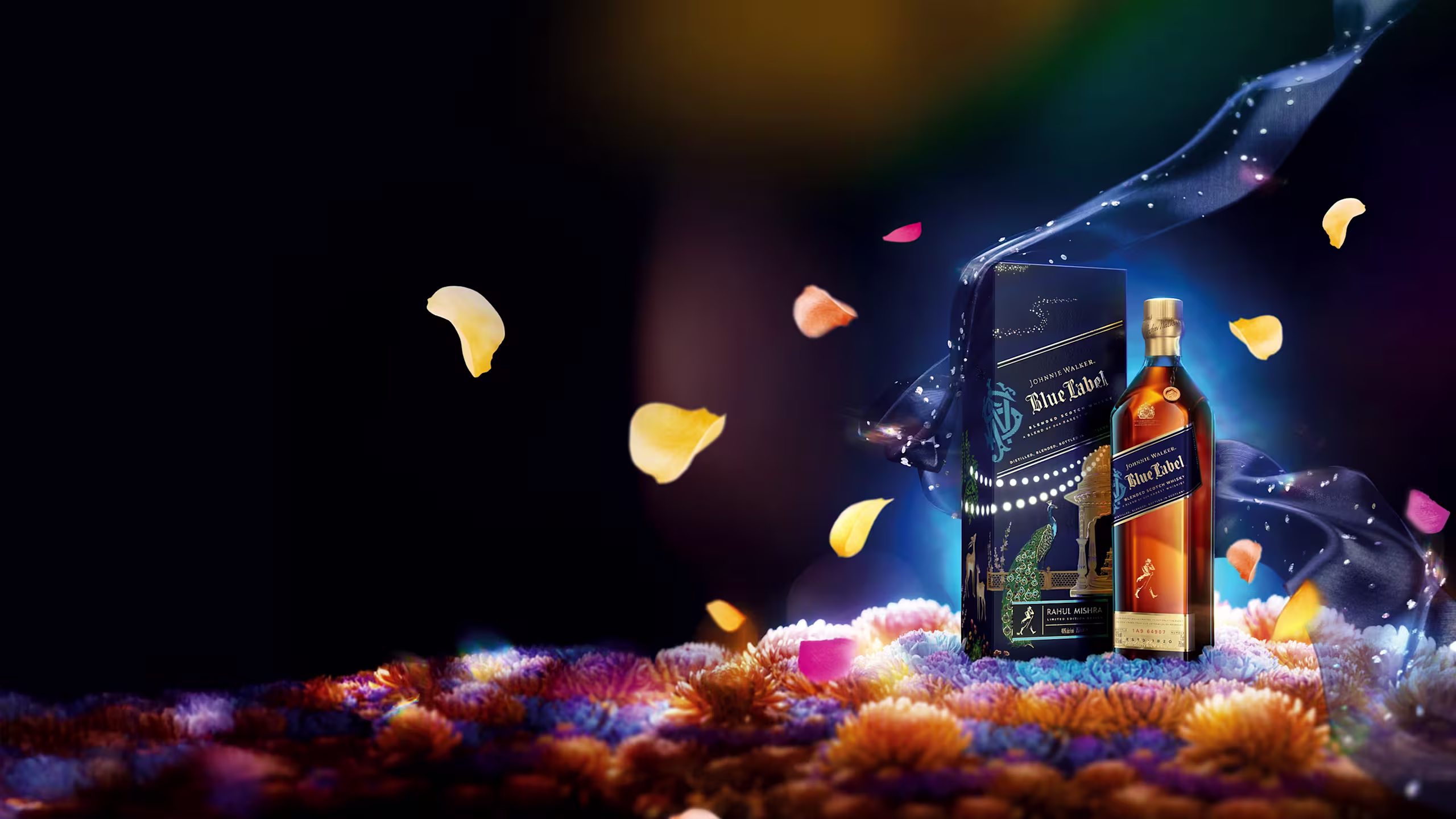 A bottle and box of Johnnie Walker Blue Label whisky stand on a colorful bed of flowers, with petals floating around and blue wisps swirling in a dark, glowing background.