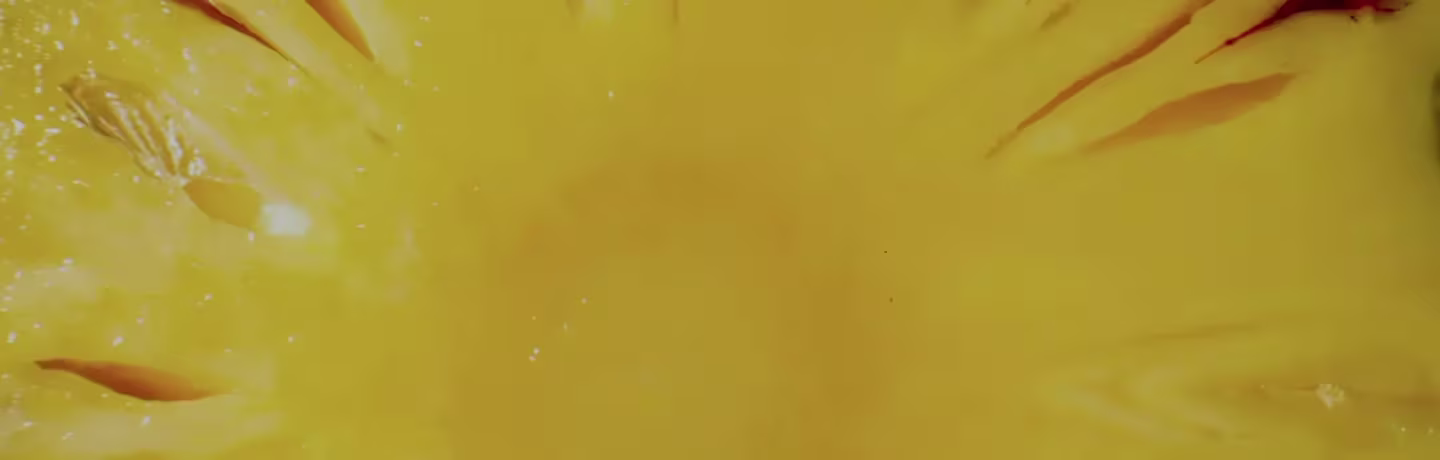 Close-up of a yellow wall with subtle texture and scattered small white spots. The surface is smooth and the tone changes slightly, creating a warm and vibrant background.