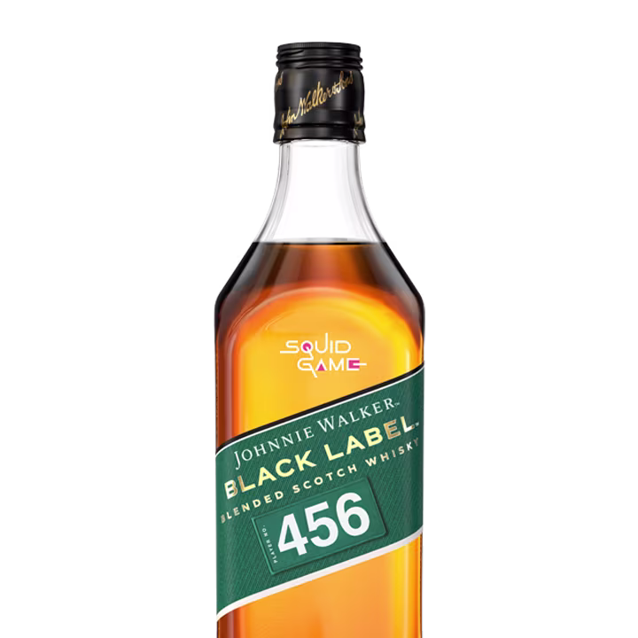 Johnnie Walker Black Label Squid Game Edition. A bottle of Johnnie Walker Black Label Blended Scotch Whisky with a green label and a 456 number. The cap has gold lettering, and the bottle also features Squid Game text in light purple and pink.