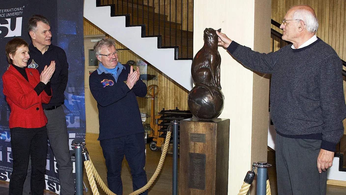 scientists stand next to bronze cat statue memorializing first cat in space