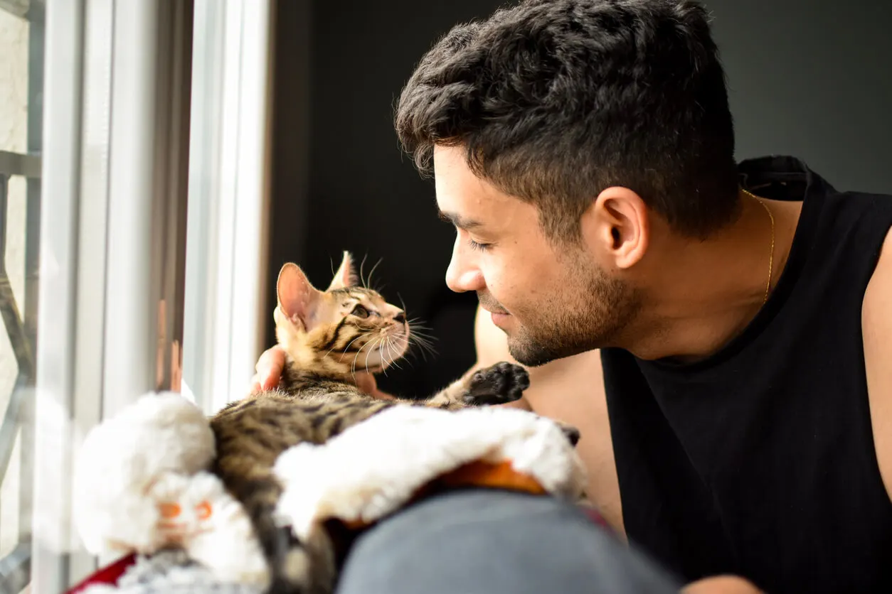 man with his kitten in front of window