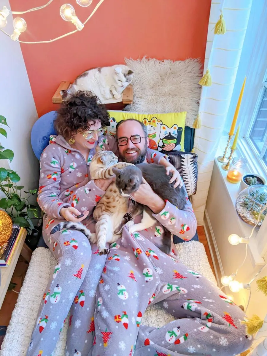 couple in pajamas poses with cats in bed