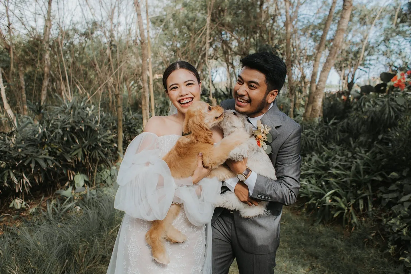 married couple poses for wedding pics with dogs in hand