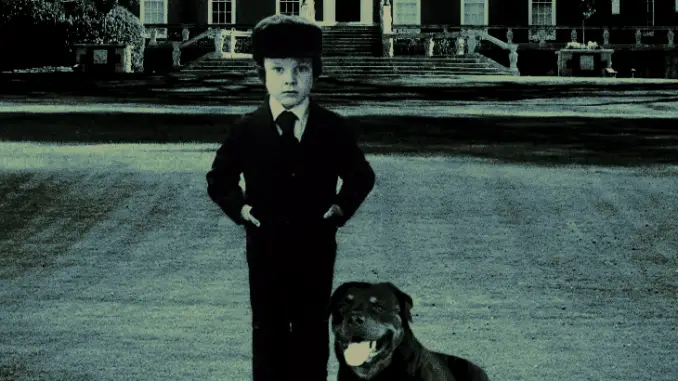 young boy stands with rottweiler by his side