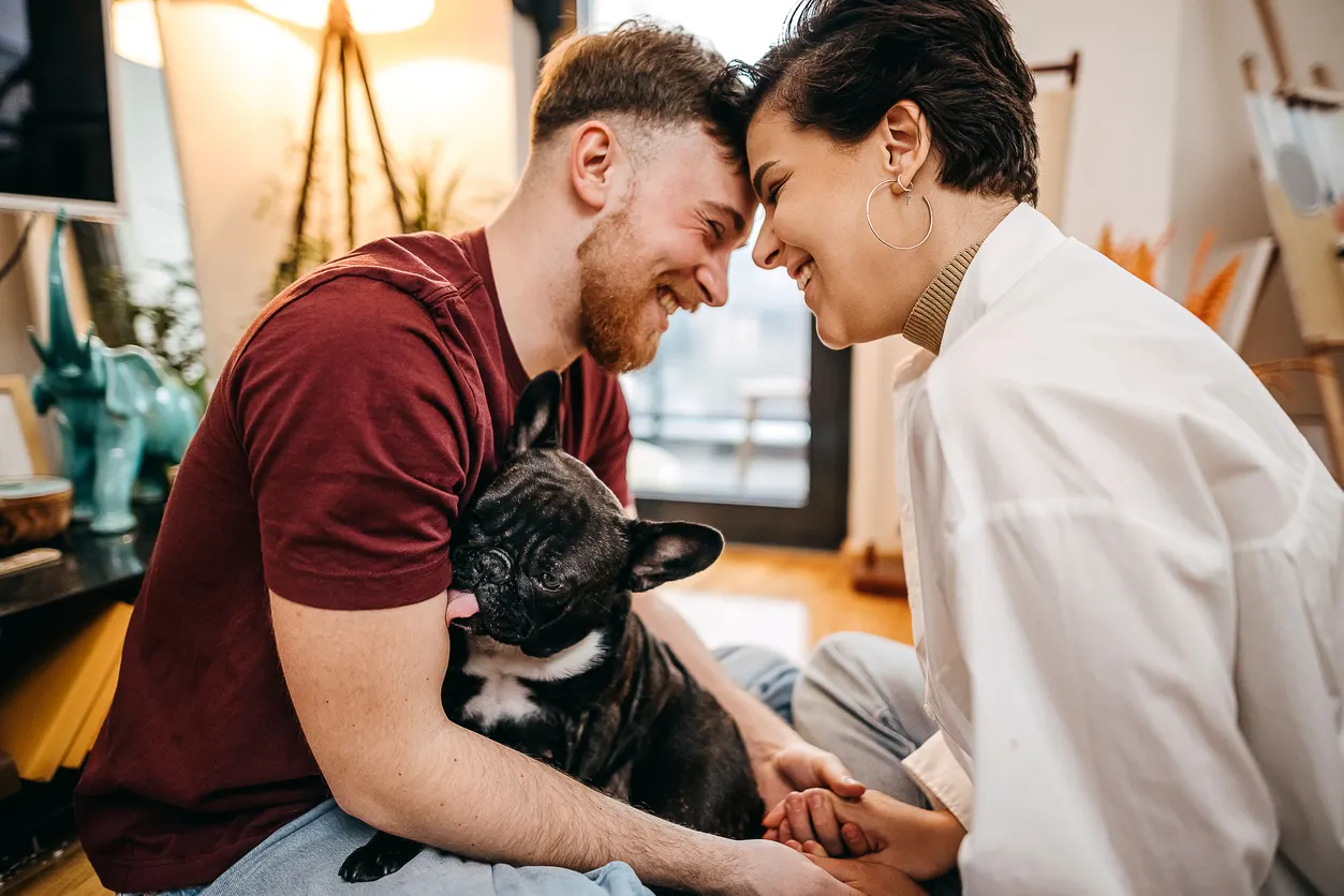 young couple embracing at home with dog in their lap