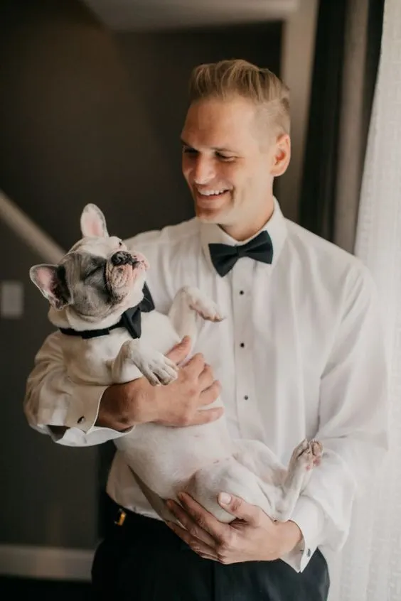 Man holding small dog wearing bowtie for wedding