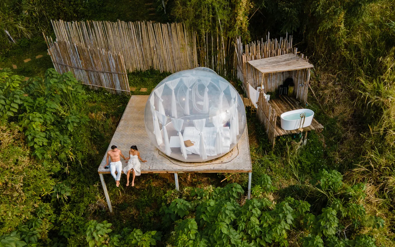 couple sitting in jungle in front of Airbnb glamping dome