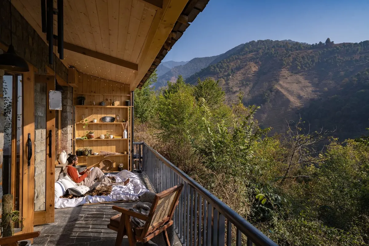 Man relaxing on treehouse porch in India overlooking the mountains