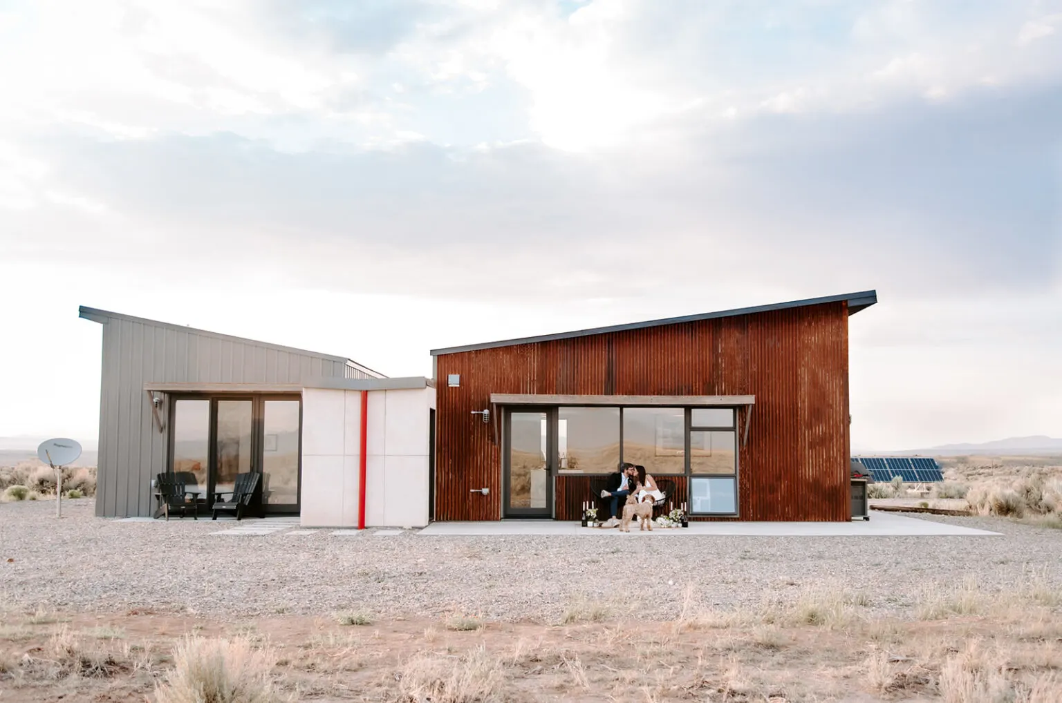 modern taos house with couple posed for elopement out front