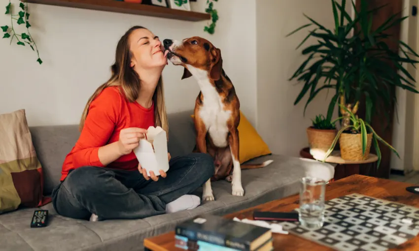 woman eating carry out food and kissing dog