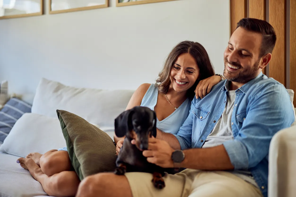 couple sits on couch with dog in lap