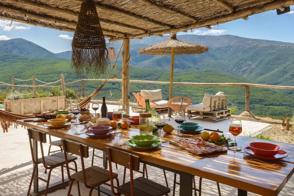 large dining table on patio of spanish airbnb overlooking mountains