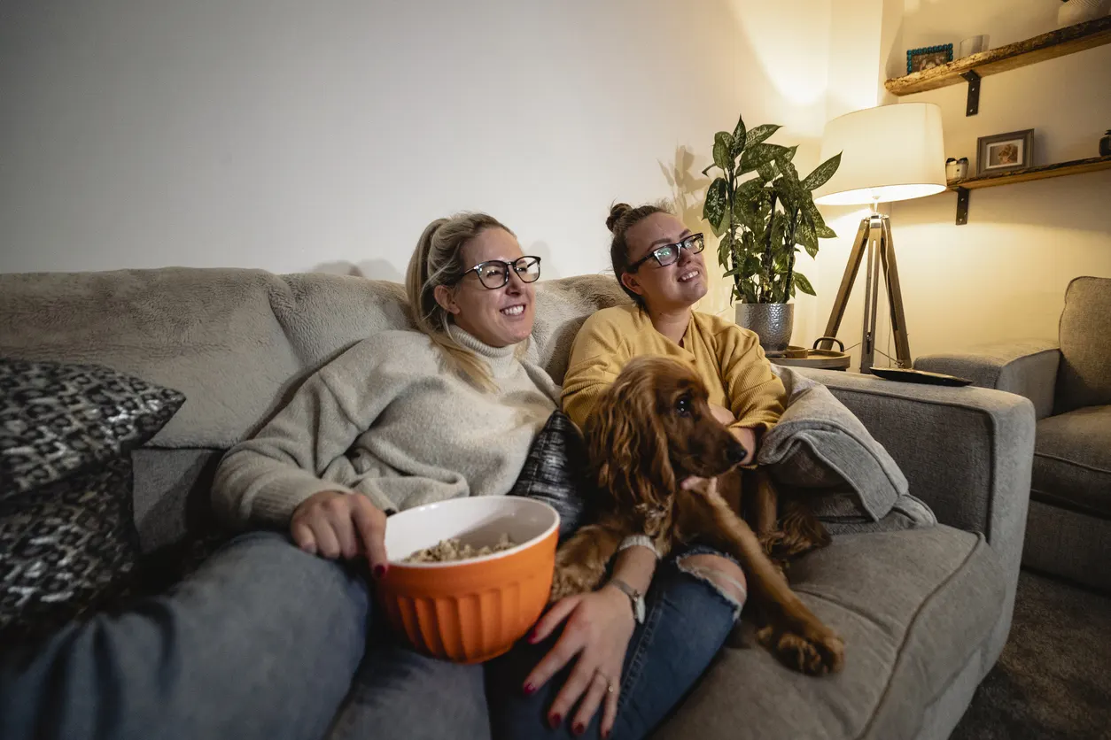 dog watching tv with two women