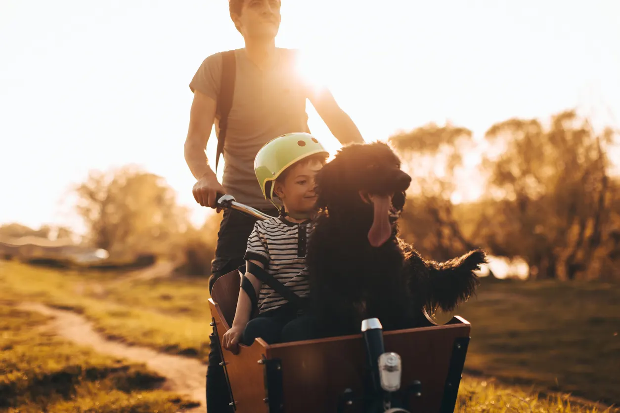 Dad wheels child around in wagon with dog in front