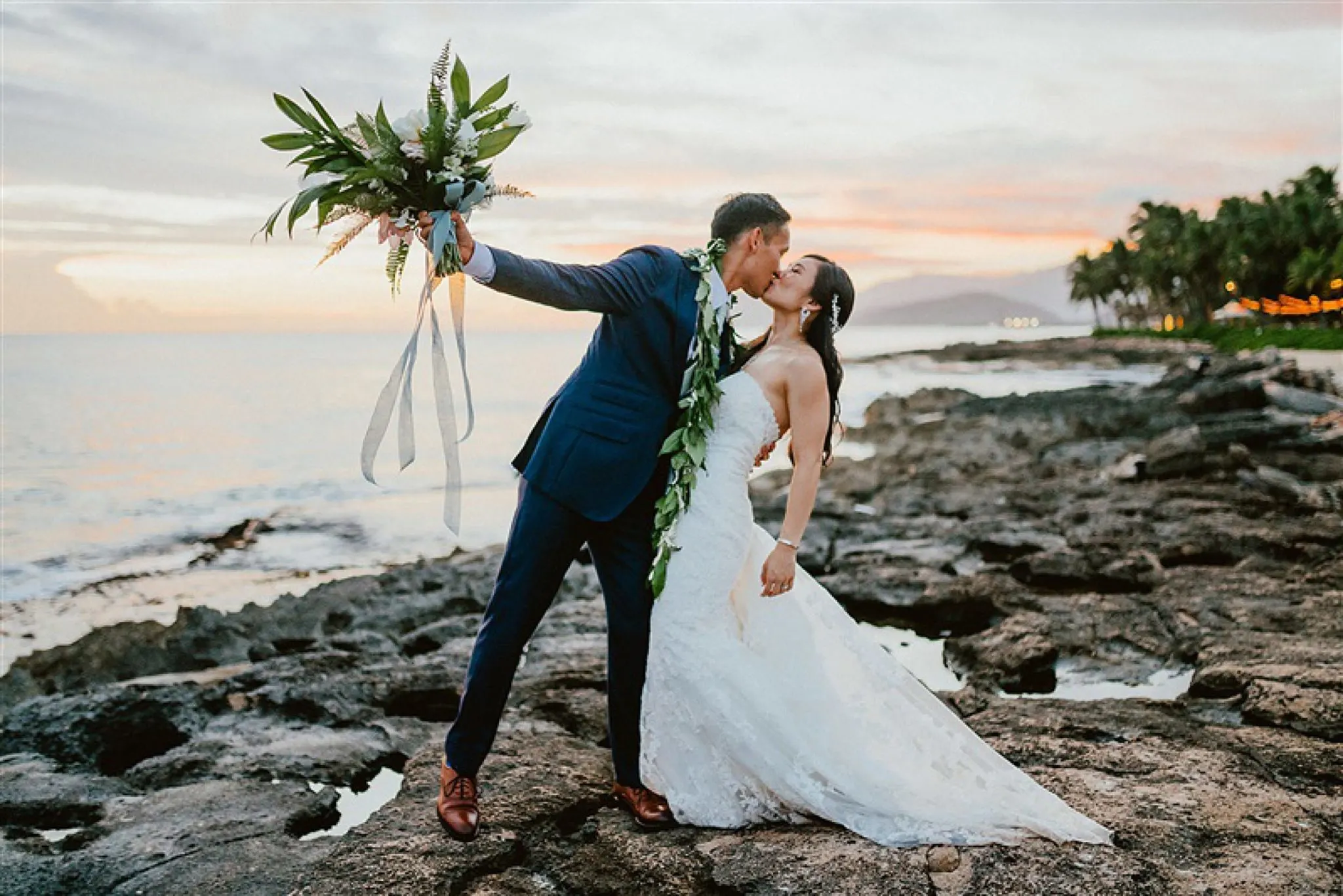 couple kissing on rocks in oahu hawaii after wedding