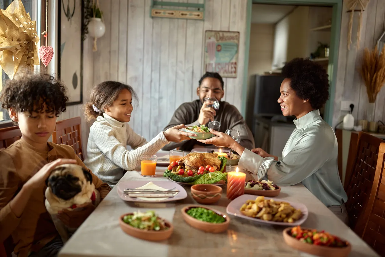 Happy family enjoying dinner at dining table with dog