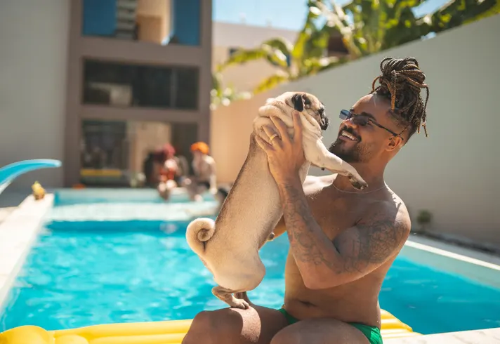 man holding pug at pool party