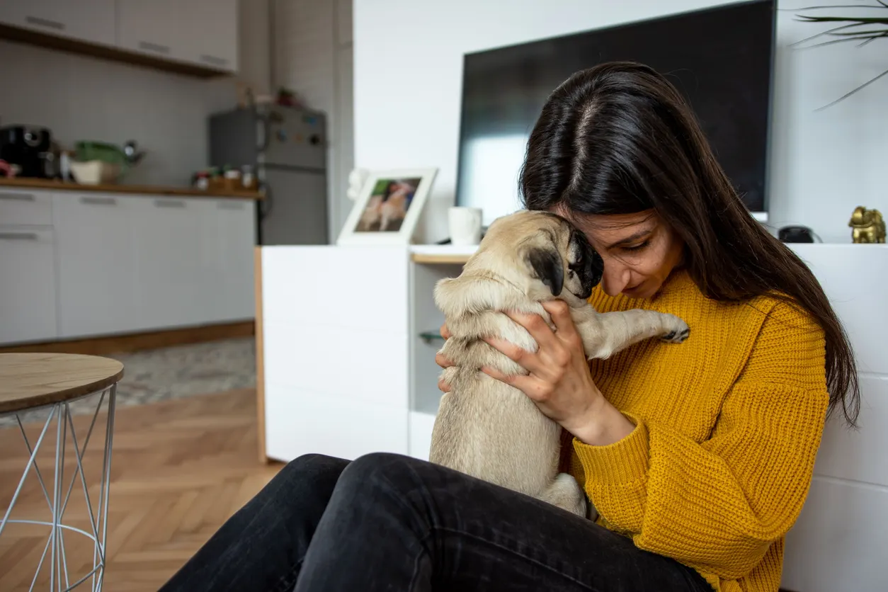 woman leans into dog looking sad