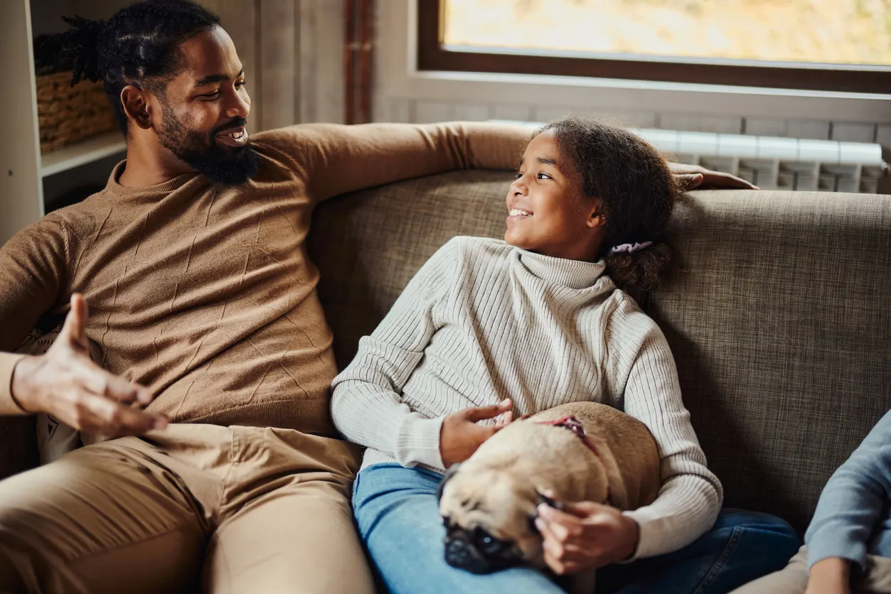 dad and child talking with pug in lap