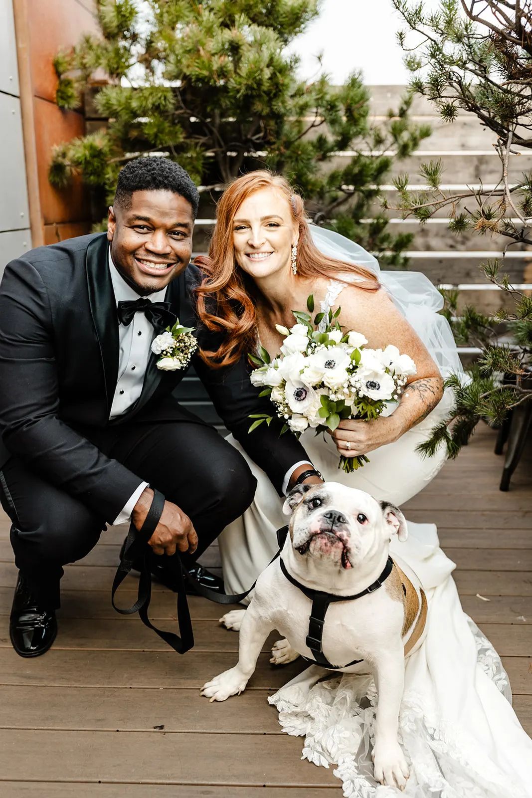 couple on wedding day posing with dog and bouquet