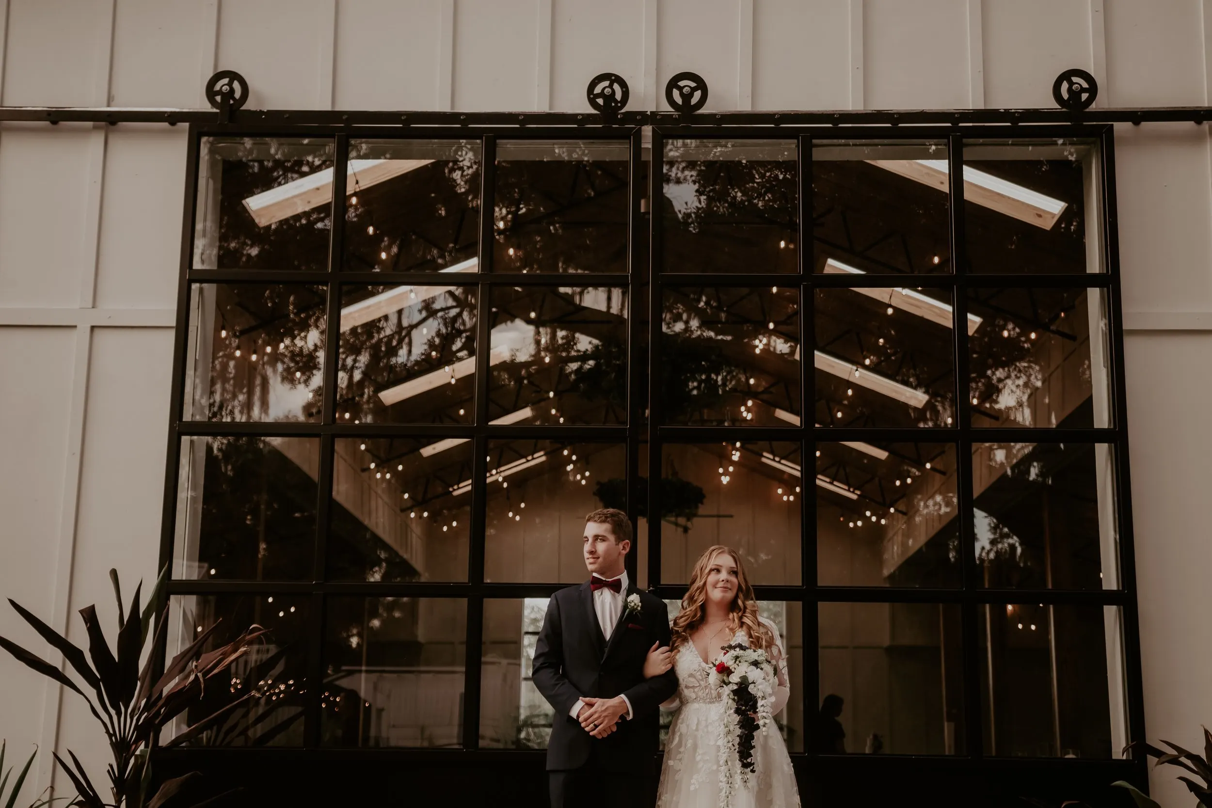 couple posing for wedding photos outside of large barnhouse