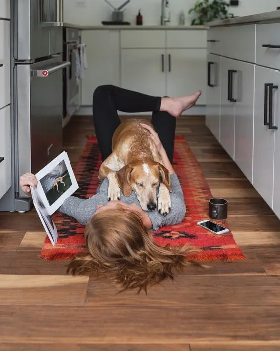dog and woman laying together on rug in kitchen